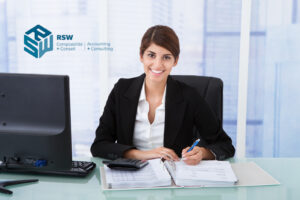 Confident Businesswoman Using Calculator At Office Desk